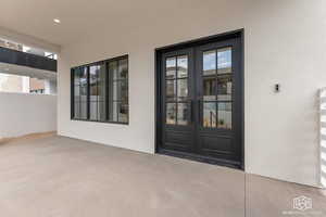 Doorway to property featuring french doors, stucco siding, and a patio