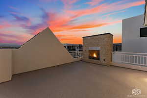 Patio terrace at dusk with a patio area and an outdoor stone fireplace
