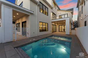 View of pool featuring a patio area, a balcony, and a pool with connected hot tub