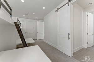 Corridor with carpet flooring, recessed lighting, a barn door, and a textured ceiling
