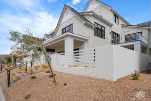 View of front of house with stucco siding and a balcony