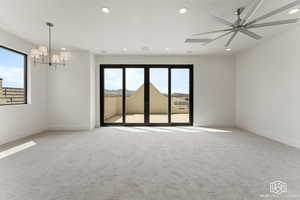 Empty room with recessed lighting, light colored carpet, ceiling fan, and a chandelier