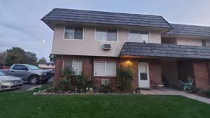 View of front of property with brick siding, mansard roof, and a front lawn