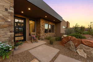 Entrance to property featuring stone siding, a patio area, and stucco siding