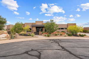 Pueblo revival-style home featuring stucco siding and stone siding