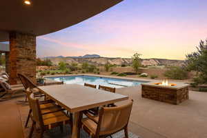 Pool at dusk featuring a patio, a mountain view, and outdoor dining area