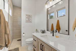 Full bath featuring vanity, tiled shower, and plenty of natural light