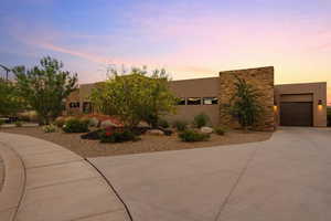 Southwest-style home with a garage, concrete driveway, stone siding, and stucco siding