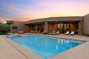 Pool at dusk featuring a patio and a pool with connected hot tub
