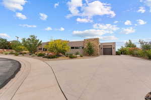 Southwest-style home with stone siding, stucco siding, and driveway