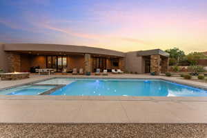 View of swimming pool with a patio, a pool with connected hot tub, and an outdoor fire pit