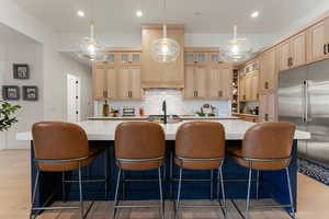 Kitchen featuring light wood-style flooring, backsplash, stainless steel built in refrigerator, decorative light fixtures, and recessed lighting