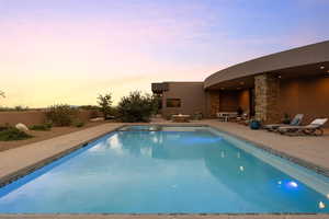 Pool at dusk with a patio and an outdoor pool