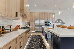 Kitchen featuring light stone counters, light brown cabinets, appliances with stainless steel finishes, and recessed lighting