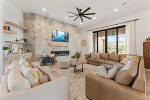 Living room with a fireplace, wood finished floors, ceiling fan, recessed lighting, and tile walls