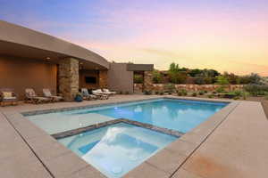 Pool at dusk with a patio and a pool with connected hot tub