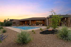 Pool at dusk with an outdoor pool and a patio