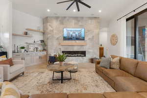 Living room featuring a fireplace, a ceiling fan, light wood finished floors, and recessed lighting