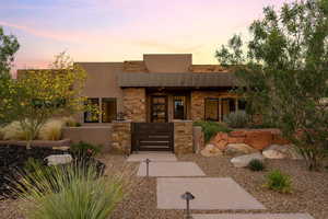 Pueblo-style home with a gate, stucco siding, a patio area, stone siding, and a fenced front yard