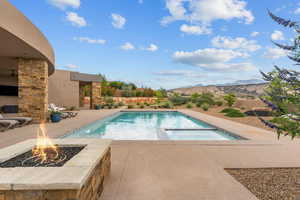 View of pool featuring an outdoor fire pit, a patio, a mountain view, and a pool with connected hot tub