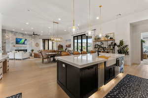 Kitchen featuring dark cabinetry, open floor plan, pendant lighting, a ceiling fan, and recessed lighting