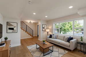 Living area with light wood finished floors, recessed lighting, stairway, and a chandelier