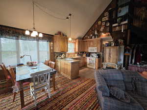 Kitchen with decorative light fixtures, light countertops, white appliances, a textured ceiling, and high vaulted ceiling