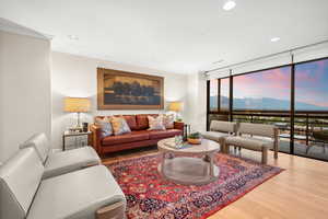 Living room with a wall of windows, light wood-style flooring, a mountain view, recessed lighting, and ornamental molding