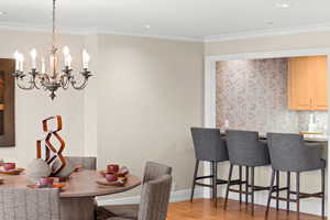 Dining space with crown molding, light wood-style floors, a chandelier, and recessed lighting