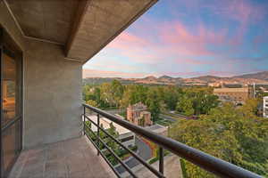 Balcony at dusk with a mountain view and view of wooded area