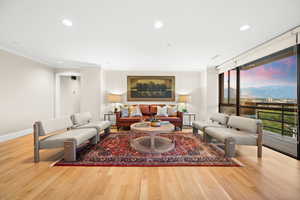 Living room featuring recessed lighting, light hardwood floors, ornamental molding, a wall of windows, and a mountain view