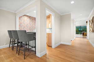 Hallway featuring ornamental molding, light wood-type flooring, and recessed lighting