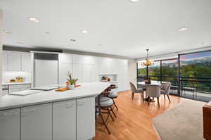 Kitchen with white cabinets, light wood-style flooring, pendant lighting, light countertops, and recessed lighting