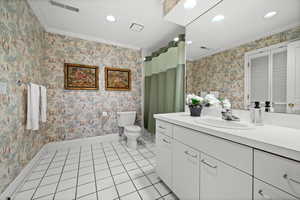 Bathroom featuring crown molding, wallpapered walls, light tile patterned floors, vanity, and recessed lighting