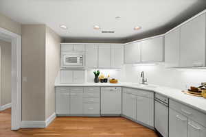 Kitchen featuring light countertops, white appliances, light wood-style floors, recessed lighting, and backsplash