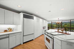 Kitchen with light countertops, white electric range, recessed lighting, light wood-style floors, and paneled built in fridge