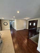 Unfurnished living room with dark wood-style flooring, a textured ceiling, and recessed lighting