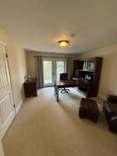 Home office featuring french doors, light colored carpet, and a textured ceiling