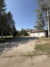View of front of house featuring asphalt driveway, brick siding, and a shingled roof
