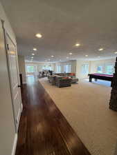 Living room with dark wood-style floors, pool table, a textured ceiling, dark carpet, and recessed lighting