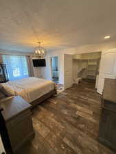 Bedroom featuring dark wood finished floors, a closet, a textured ceiling, and a chandelier