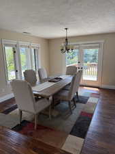 Dining room with dark wood-style flooring, a textured ceiling, and a chandelier