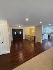Foyer with dark wood-type flooring, a chandelier, a textured ceiling, and recessed lighting