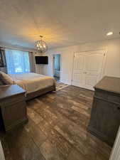 Bedroom featuring a textured ceiling, a closet, dark wood-style flooring, a chandelier, and recessed lighting