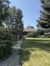 View of front of home featuring a front yard, roof with shingles, and brick siding