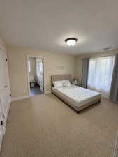 Bedroom with light carpet, a textured ceiling, and a closet