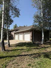 View of home's exterior with brick siding, driveway, a garage, a shingled roof, and a lawn