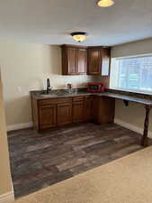 Kitchen featuring a textured ceiling, dark wood-type flooring, and dark stone countertops