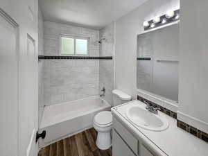 Bathroom featuring shower / bathtub combination, dark wood finished floors, and vanity