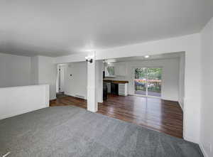Unfurnished living room featuring dark carpet and dark wood-type flooring